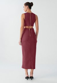 Bordová dvojdielna súprava s krátkym topom so zipsom na chrbte a priliehavou midi sukňou. Textúrovaná látka s hladkým povrchom.