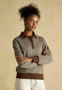 Brown and beige checkered pullover with a collared neck, button details, and ribbed cuffs, made from a textured knit fabric.