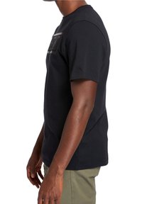 Camiseta negra de manga corta hecha de algodón, con cuello redondo y un gráfico rectangular impreso en el frente. Diseño ajustado con textura suave.