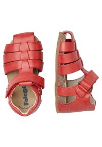 Sandali in pelle rossa con design a cinturino incrociato, lati aperti, chiusura con fibbia regolabile e suola di colore naturale.