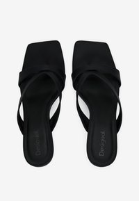 Schwarze Sandalen mit offener Zehenpartie, einem quadratischen Zehendesign, mehreren überkreuzten Riemen, einer glatten Textur und einer flachen Sohle.