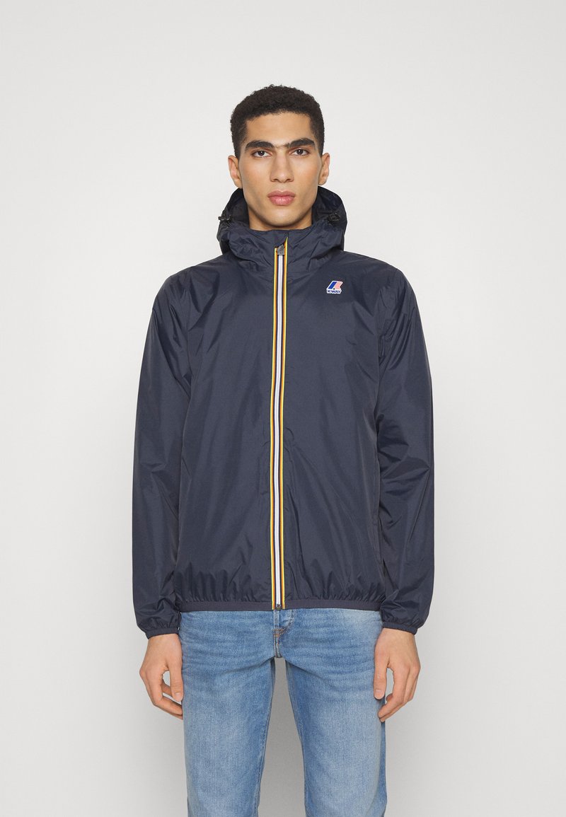 Marinefarbene Regenjacke mit Kapuze, ausgestattet mit gelben Reißverschlussdetails und elastischen Ärmeln, aus wasserdichtem Material, lässige Passform.