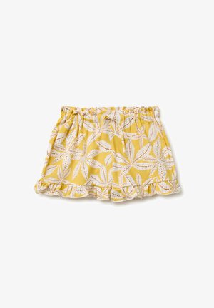 Pantalones cortos amarillos con cintura elástica, con patrones de hojas blancas y marrones y dobladillos con volantes, colocados planos sobre un fondo blanco.