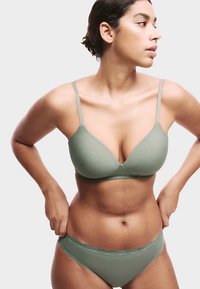 Jasnozielony zestaw bielizny składający się z gładkiego, usztywnianego biustonosza z cienkimi ramiączkami oraz dopasowanych fig z koronkową lamówką. Miękka faktura materiału.