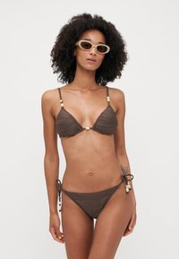 Brown ribbed bikini with a triangular top and adjustable side-tie bottom, accented with beads on straps and ties. Textured fabric.