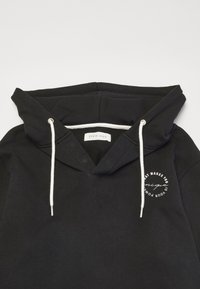 Felpa nera con scollo a V, lacci bianchi e una grafica circolare sul petto. Materiale in morbido cotone, vestibilità rilassata.