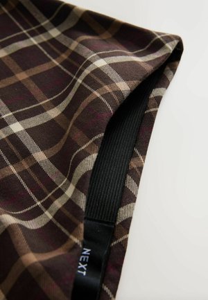 Brown plaid fabric featuring intersecting lines in beige, cream, and burgundy. Includes a black elastic band and label with "NEXT."