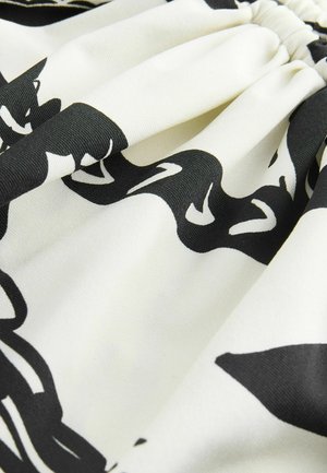 Zwart-witte katoenen stof met een vloeiend, abstract patroon en een lichte glans; gerimpeld aan de taille, zacht en soepel.