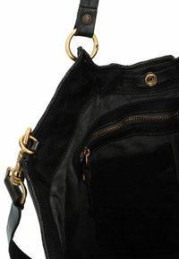 Interno di una borsa in pelle nera con hardware dorato, dotato di tasca con zip e fodera in tessuto testurizzato. Design aperto per un facile accesso.