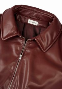 Giacca in ecopelle borgogna con chiusura a zip frontale, grande colletto e texture liscia; presenta un'etichetta con la scritta "OH APRIL."