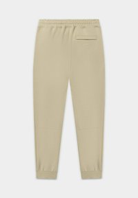 Beige joggingbroek met een elastische tailleband, taps toelopende pijpen en een achterzak, gemaakt van zachte stof met een gladde textuur.