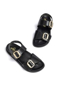 Sandalias negras con dos correas anchas y hebillas doradas, plantilla texturizada y suela plana, fabricadas con material sintético duradero.