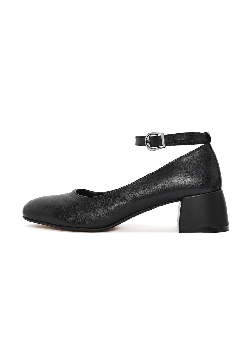 Zapato de tacón medio de cuero negro con puntera redondeada, tira en el tobillo y acabado texturizado. Cuenta con un sólido tacón cuadrado para mayor soporte.