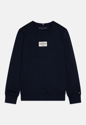 Felpa blu navy con scollatura a girocollo, polsini e orlo a costine. Presenta un logo rettangolare in bianco, rosso e blu.