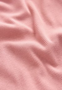 Tela de color rosa claro con textura acanalada y suave, mostrando pliegues y contornos sutiles que resaltan la elasticidad y el patrón del material.