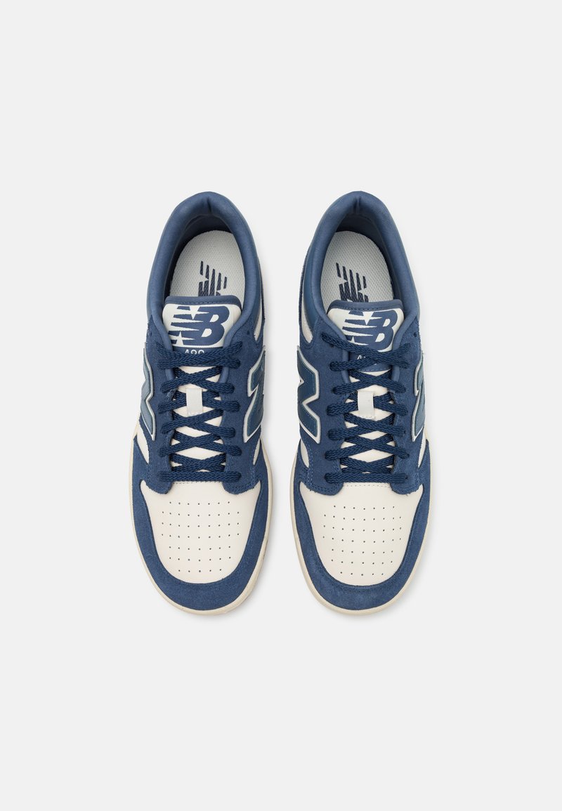 Ein Paar blaue und weiße New Balance Sneakers mit Schnürsenkeln, von oben auf einem weißen Hintergrund betrachtet.