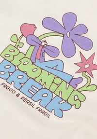 Personne portant une veste violette et un pantalon bleu se détend parmi de grandes fleurs stylisées violettes et roses avec des tiges vertes et le texte « Pause florissante ».