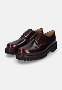 Bordeauxfarbene Leder Schuhe mit glänzender Oberfläche, runder Zehenform, dicker schwarzer Sohle und klassischem Schnürdesign. Glatte Textur mit minimalen Akzenten.