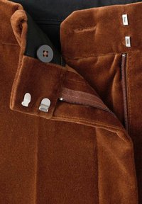 Bruine corduroy broek met een rits- en knoopsluiting. Voorzien van metalen hardware en een zachte, gestructureerde stof.