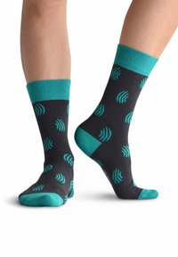 Calcetines negros con acentos en color teal, presentan un patrón de olas repetido. Puño acanalado en el tobillo y una textura suave en todo el calcetín.