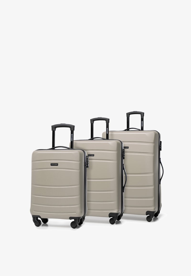 Tři tvrdé kufry ve světle šedé barvě, s rýhovaným designem, černými rukojetmi a kolečky otočnými o 360 stupňů pro snadnou mobilitu.