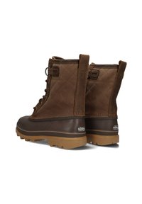 Brown quilted waterproof boots with lace-up front, rubber soles, and logo detail; designed for durability and traction in cold conditions.