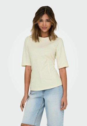 Hellgelbes T-Shirt mit kurzen Ärmeln und rundem Halsausschnitt, kombiniert mit hellblauen Jeansshorts mit ausgefransten Rändern.