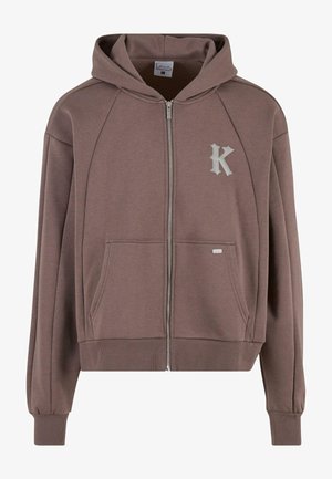 Brūna zip-up kapuce ar kapuci, ribotām aprocēm un apakšmala, lielām priekšējām kabatām un sudraba "K" logotipu kreisajā krūtī. Mīksts materiāls.