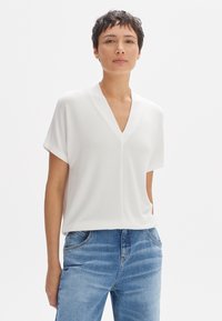 Witte top met korte mouwen en een V-halsontwerp, gemaakt van zachte stof. Gecombineerd met lichtblauwe denim jeans, met klassieke vijf-pocket styling.