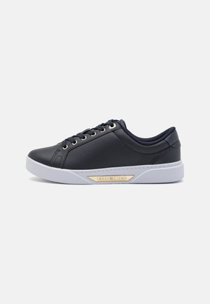 Zwarte synthetische sneakers met gouden veteroogjes en logo-accent. Witte rubberen zool, ronde neus en gewatteerde kraag voor comfort.