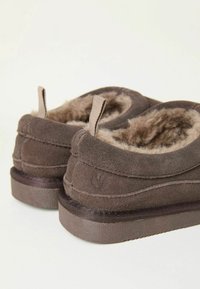 Brown suede slippers with soft fur lining, round toe, and two pull tabs. Textured sole for grip and plush interior for comfort.
