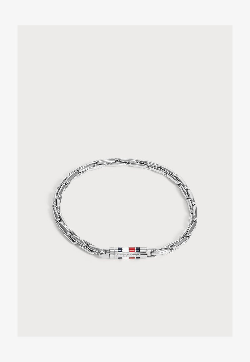 Bracelet chaîne en argent avec des maillons allongés et un fermoir cylindrique présentant des rayures rouges, blanches et bleues sur un fond uni.