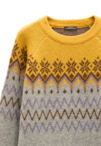 Sweter dziergany w kolorach żółtym, szarym i fioletowym, zdobiony geometrycznymi wzorami i motywami śnieżynek. Miękka faktura z prążkowanym dekoltem i rękawami typu raglan.