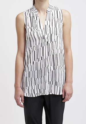 Ærmeløs hvid bluse med sorte, vertikale og diagonale striber, V-hals krave, båret med sorte bukser.