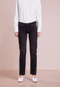 Černé džíny z denimu se rovný fit, předními kapsami a zapínáním na knoflík, doplněné o přiléhavou bílou košili. Hladká textura látky.