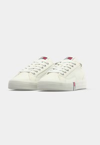 Λευκά πάνινα παπούτσια με στρογγυλή μύτη,  κορδόνια, λαστιχένια σόλα και οριζόντια ρίγα σε κόκκινο, λευκό και μπλε στη πλευρά.