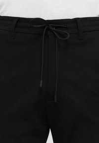 Black pants with a smooth texture, featuring a drawstring closure and reinforced waistband. Simple design with no visible patterns or accents.