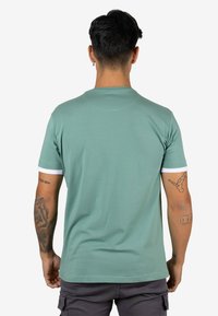 Camiseta verde de manga corta con cuello redondo y detalles blancos en las mangas. Textura suave y diseño ajustado.