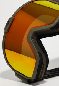 Ski goggles med en orange spejlelinse, olivengrøn ramme, sort skumpolstring og et tekstureret rem med et stribet mønster.