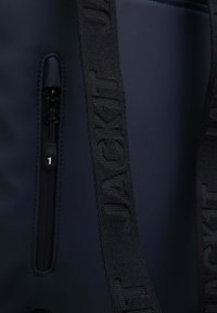 Borsa blu navy con superficie testurizzata, dotata di una tasca con zip e di una robusta tracolla nera con scritta del marchio incisa.