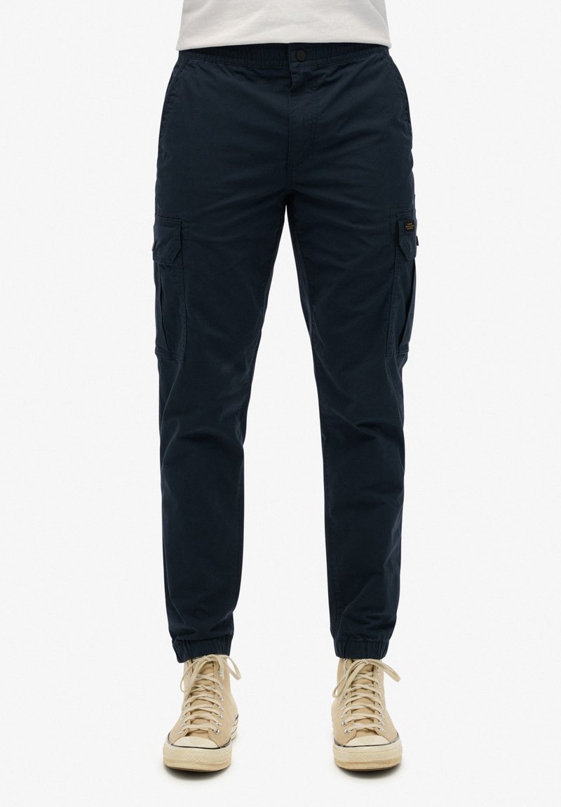 Pantalons cargo bleu marine avec poches latérales, poignets élastiques et taille ajustée. Confectionnés en tissu doux, ils présentent un design décontracté adapté à diverses occasions.