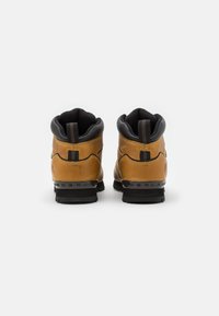 Stivali da hiking in pelle marrone con accenti neri, colletto imbottito e suola testurizzata. Presenta un'etichetta a taglio ad anello e un dettaglio del tallone con marchio.