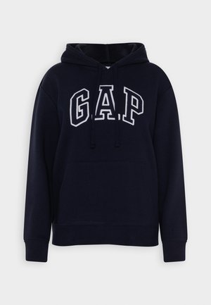 Tummansininen huppari, jossa on etutasku, kiristettävä hupun naru ja valkoisella ääriviivalla varustettu "GAP"-teksti rinnassa.
