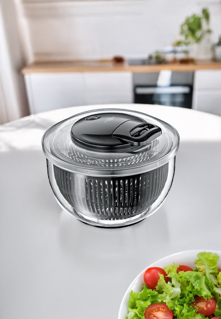 Klarer Glas-Salatschleuder mit einem schwarzen Deckel und Griff, ausgestattet mit einer gerippten Innenfläche für das Abfließen und einer glatten Außenfläche.