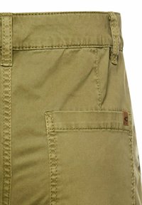 Khaki shorts featuring a smooth fabric, a side pocket, and reinforced stitching at the waistband. Includes a small logo patch.