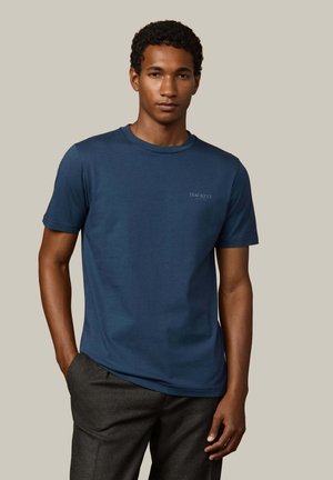 Marineblaues Baumwoll-T-Shirt mit Rundhalsausschnitt und kurzen Ärmeln, versehen mit einem dezenten Logo auf der linken Brust. Glatte Textur, lässige Passform.
