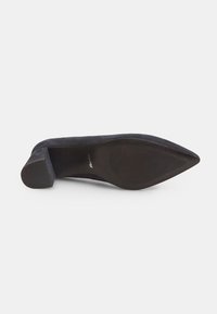Scarpa nera in suede con tacco alto, punta affilata e suola in gomma testurizzata. Superficie superiore liscia con accenti minimi e tacco robusto.