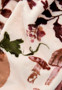 Fleece deka s jemnou strukturou a pudrově růžovým pozadím, na kterém se nachází botanické vzory v zelených, hnědých a jemně růžových odstínech.