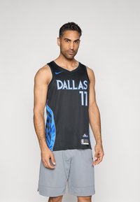 Schwarzes Basketballtrikot mit blauen Akzenten, mit "DALLAS" und "11" in fetter Schrift, aus Mesh-Gewebe gefertigt. Die Shorts sind hellgrau.