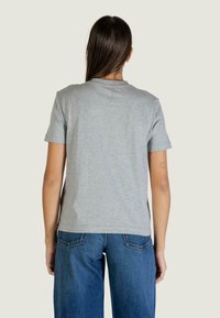 Szara bawełniana koszulka z krótkimi rękawami, okrągłym dekoltem i prostym krojem. W zestawieniu z niebieskimi dżinsami z wysokim stanem, prezentuje casualowy styl.